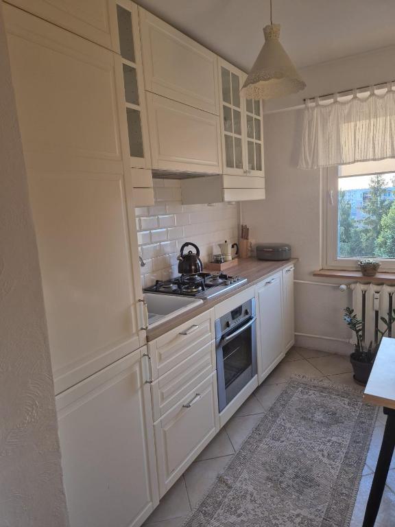 a kitchen with white cabinets and a tea kettle at Apartament Jaroty dla 4 osób in Olsztyn