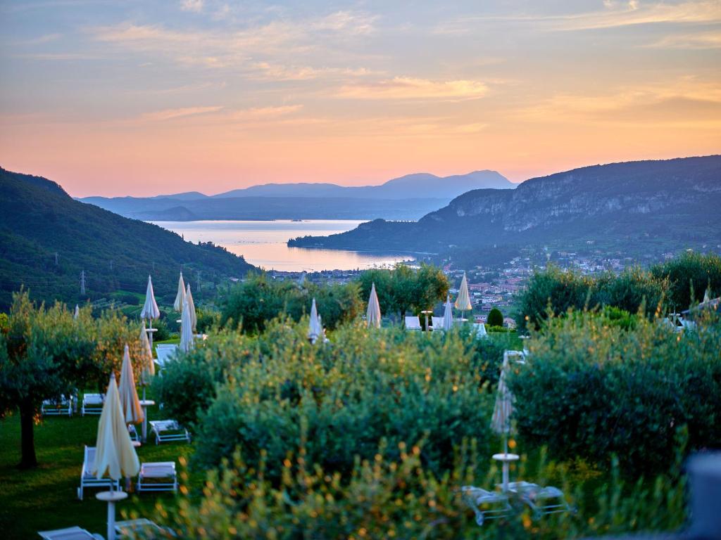 a view of a lake and mountains with umbrellas at Hotel Boffenigo - The Golden Hour in Costermano