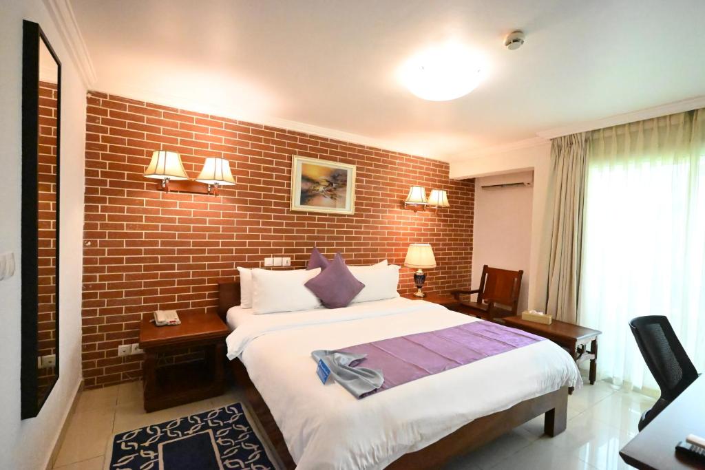 a bedroom with a large bed and a brick wall at Aeroport Grand Hotel in Douala