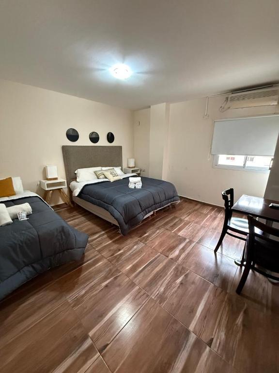a bedroom with two beds and a table and a desk at Del Fundador in Córdoba