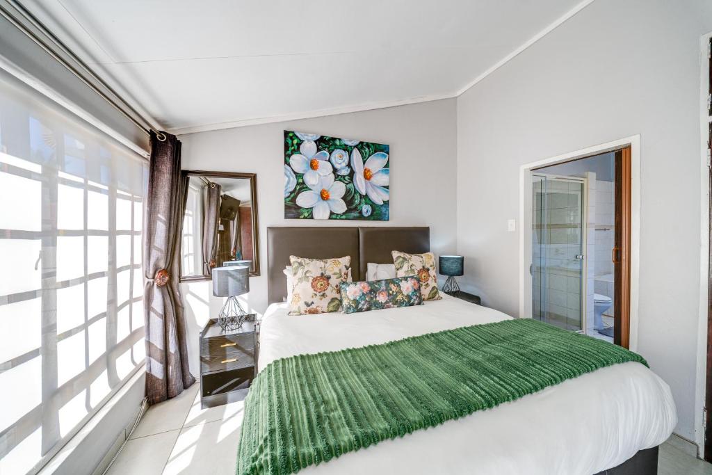 a bedroom with a large bed with a green blanket at 22 on Nicol in Secunda