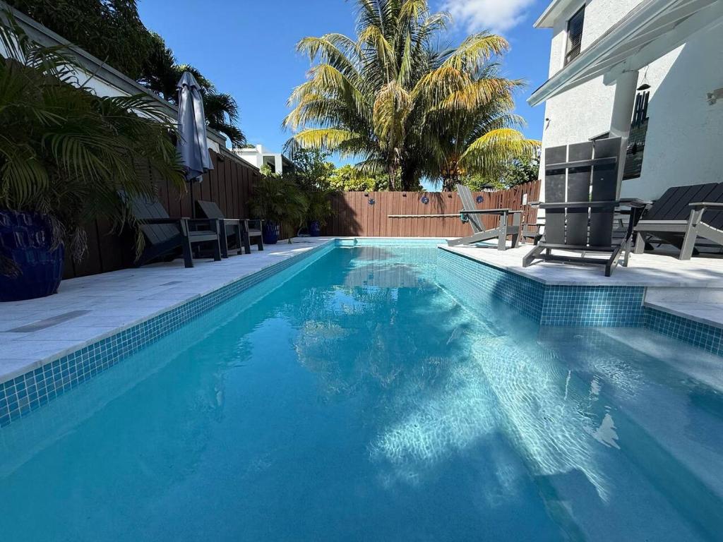 a swimming pool with two chairs and a palm tree at The Miami Grove Oasis in Miami