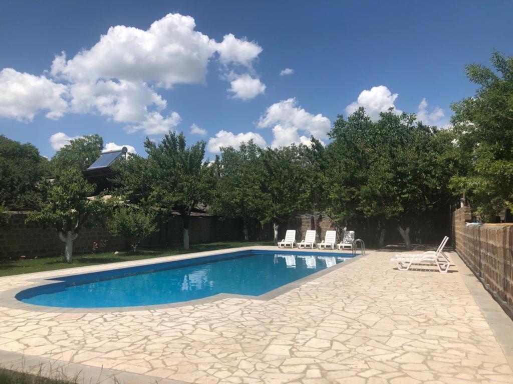 a swimming pool in a yard with chairs and trees at Yvette B&B in Garni