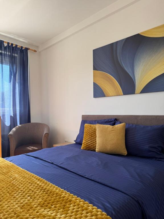 a bedroom with a blue bed with a painting on the wall at Apartman Lambros 2 in Soko Banja