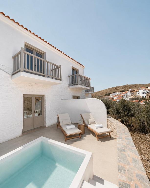 a white house with a swimming pool and two chairs at Dryope Luxury Living in Dhriopís