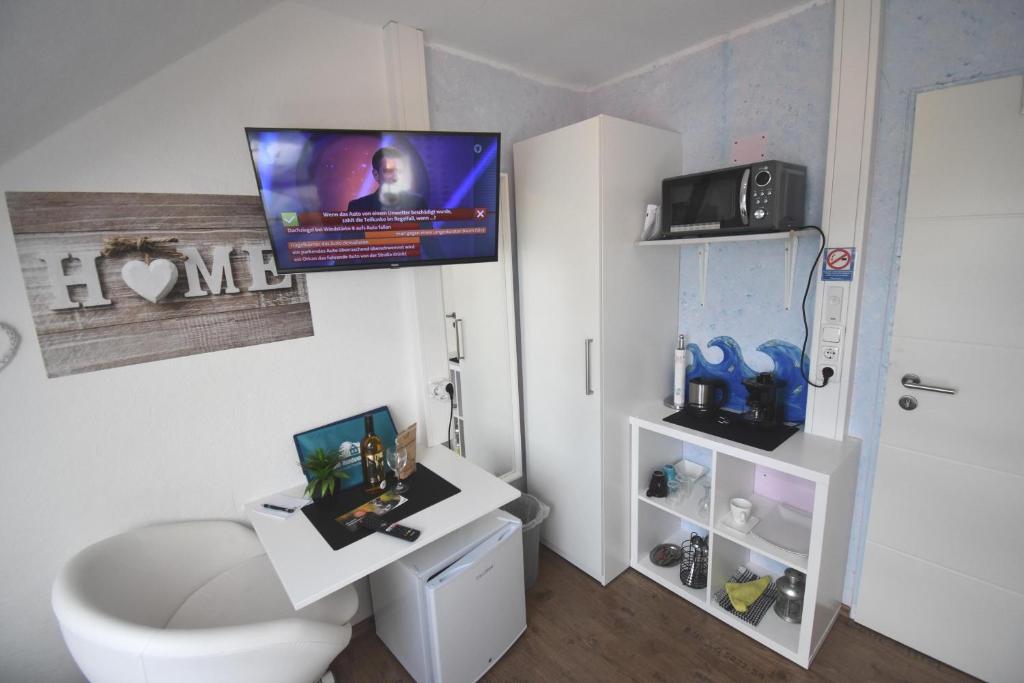 a bathroom with a toilet and a tv on the wall at Ferienappartment Lhasa Apso in Dornum