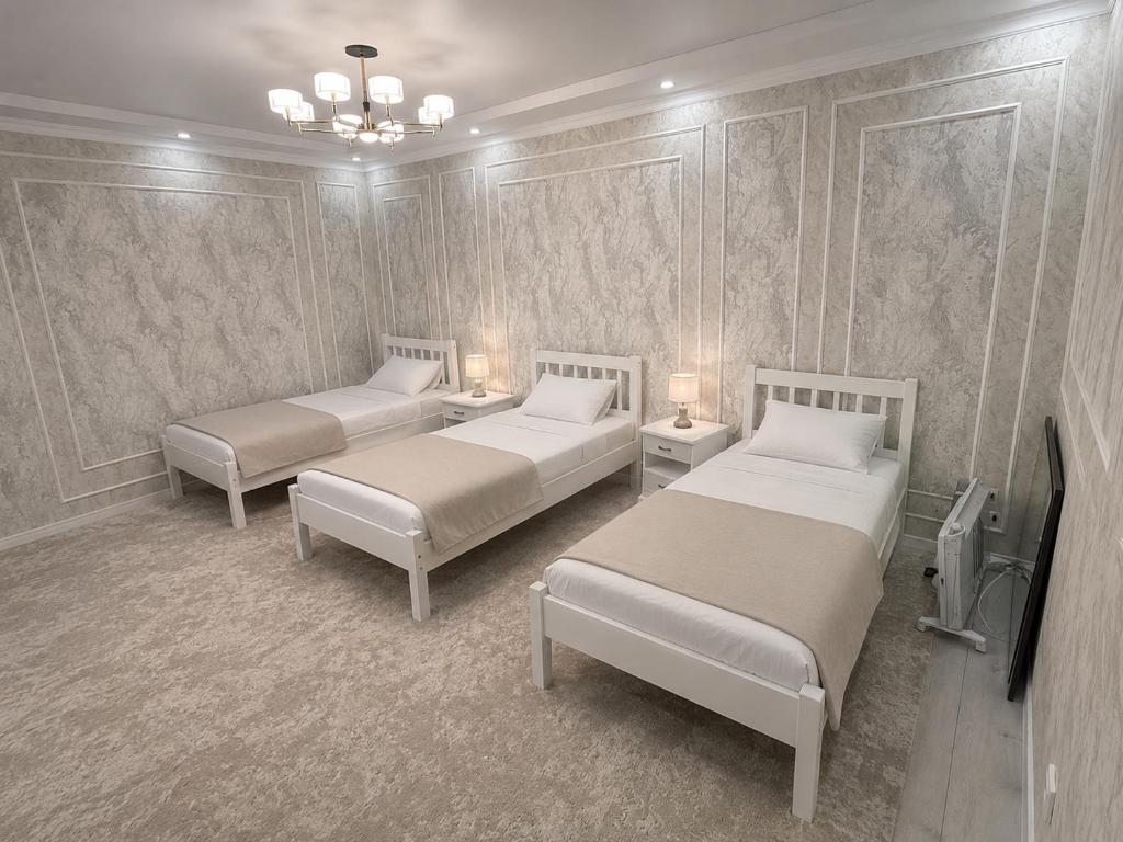 a room with two beds and two tables with lamps at Гостевой дом 64 in Naryn