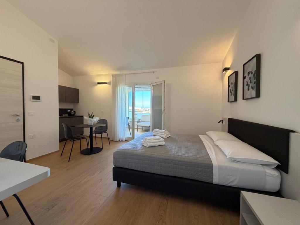 a bedroom with a bed and a kitchen and a table at Mediterranea Apartments Sunrise in Assemini