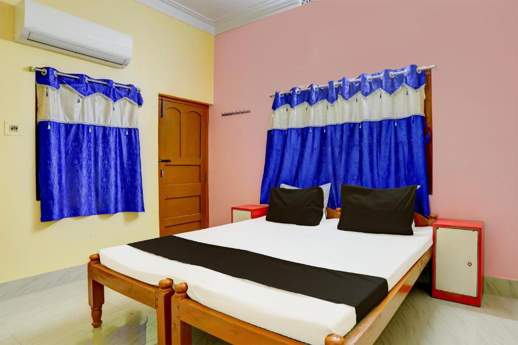 a bedroom with a bed with blue curtains at Super Hotel O A.R. Lodge in Durgāpur
