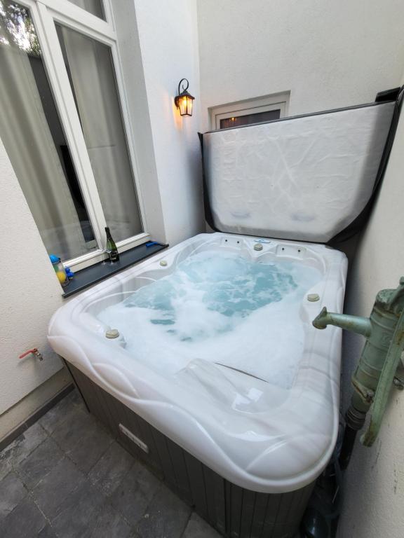 a bath tub in a room with a window at Castle-grounds house with rooftop view & jacuzzi in Ghent