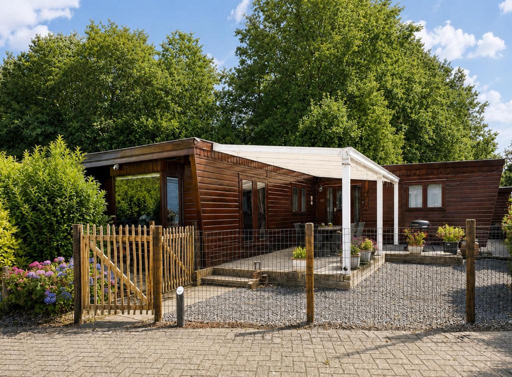a small wooden cabin with a fence in front of it at Rustiek Boschalet Sven Veluwe met Omheinde Tuin in Putten
