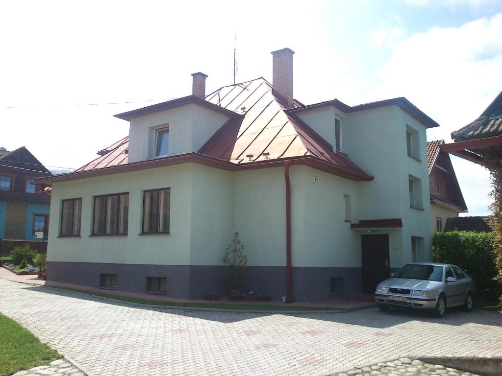 a white house with a car parked in front of it at Privat 107 in Pavčina Lehota