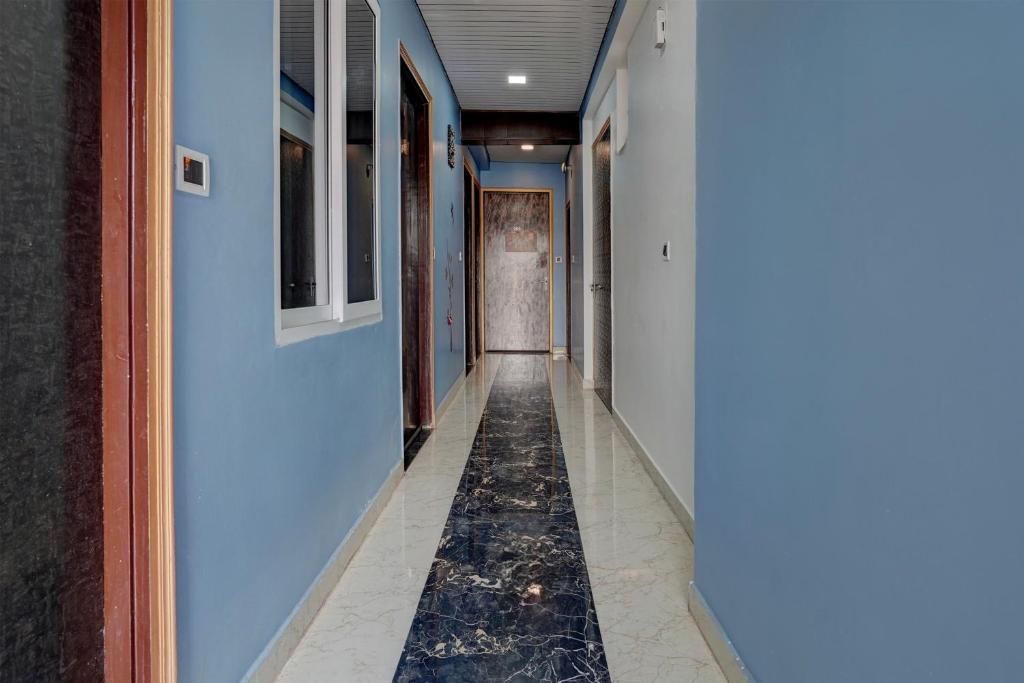 a hallway with blue walls and a tile floor at Hotel O Swastik Inn in Chinhat