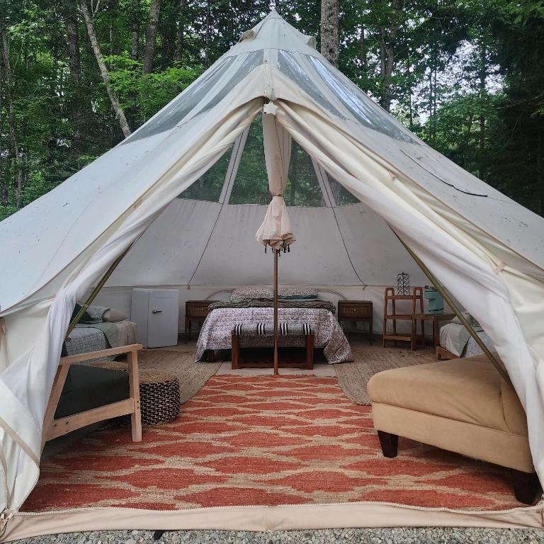 a tent with a bed and a couch and a rug at Flatrock on the River Topknot in Frankfort
