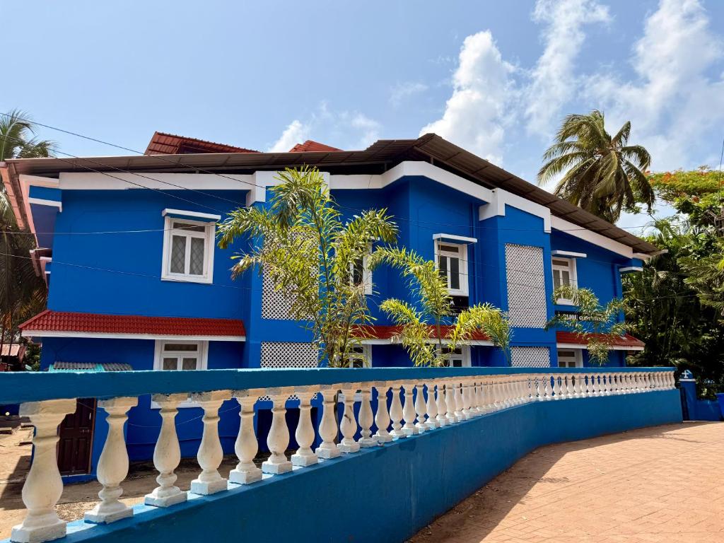 a blue house with a white fence at Bijou Guest House in Baga