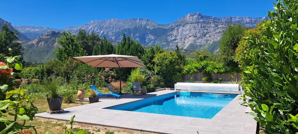 a swimming pool with an umbrella and a chair and a table at Chambre d'hôte de Reymure in Vif