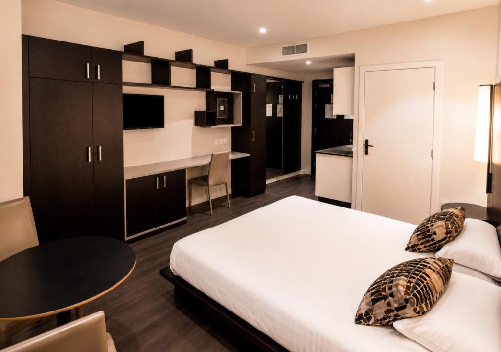 a bedroom with a bed and a table and a kitchen at Résidence Les Alizés Bordeaux Sud - La Brède in La Brede