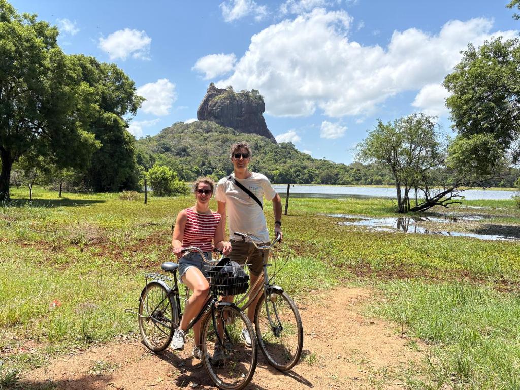 a man and woman riding bikes in front of a rock at Sigiri Shen Residence in Sigiriya