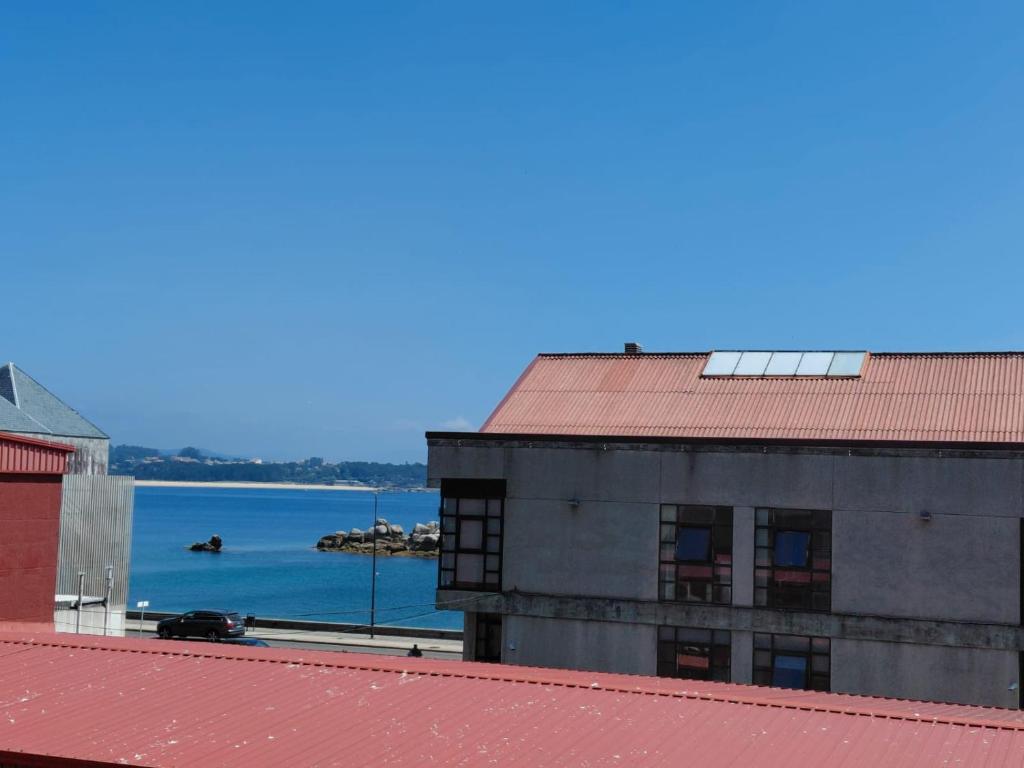 a building with a red roof with a view of the water at Pedra Pateira 1 in Ribeira