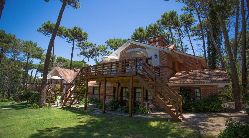 a large house with a wooden staircase in the yard at Posada del Bosque By HS in Carilo