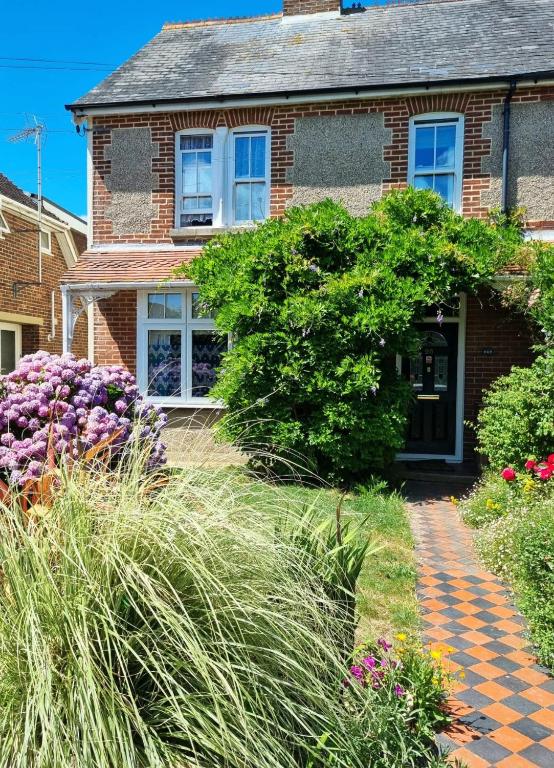 a brick house with flowers in front of it at The Witterings Bed and Breakfast in Chichester