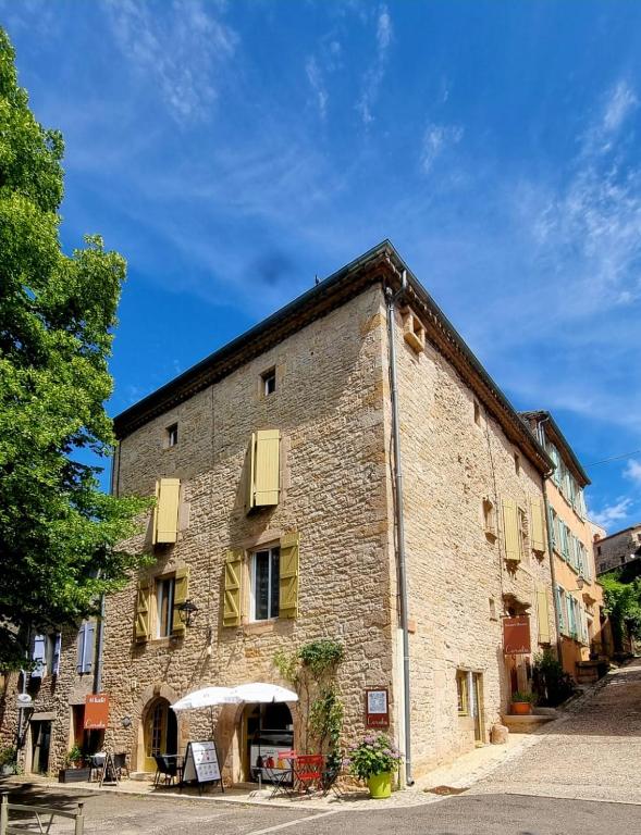 an old brick building with yellow shutters on a street at Sweet Home Cornelia in Bruniquel