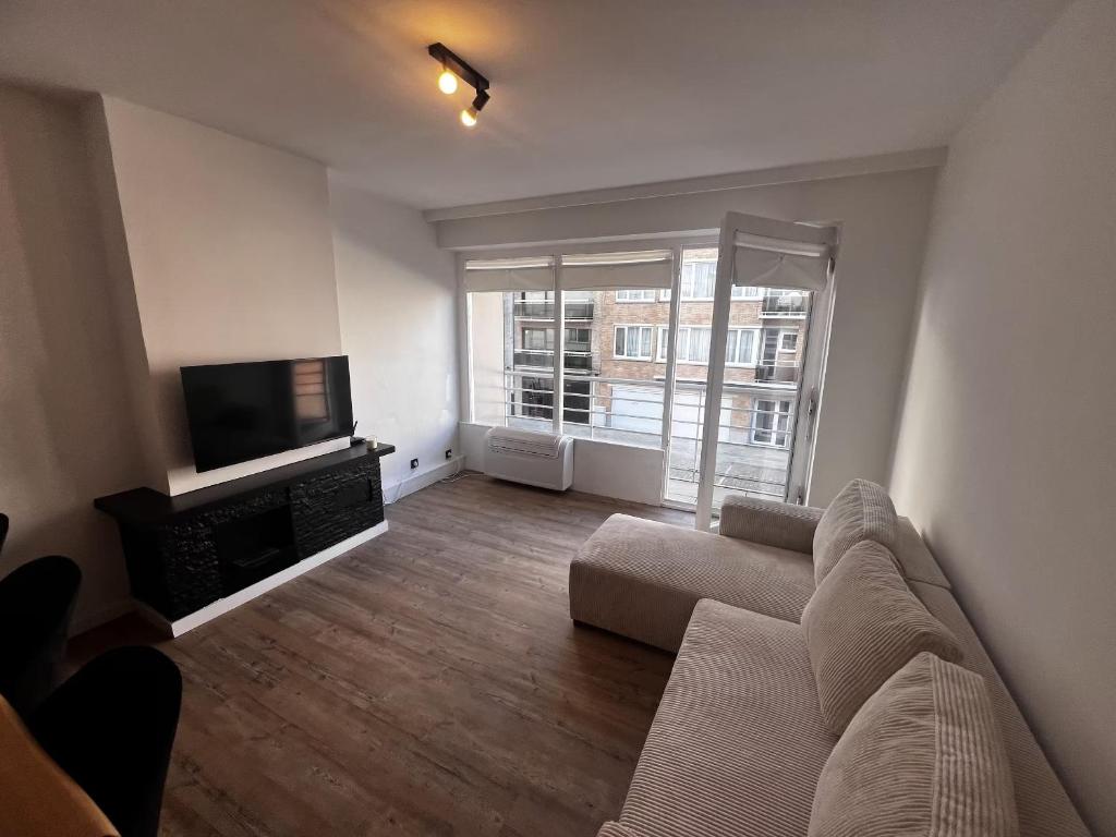 a living room with a couch and a flat screen tv at Studi'eau2 in Ostend