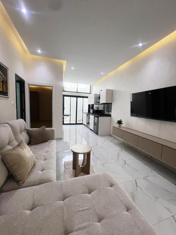 a living room with a large couch and a flat screen tv at La Casa Residence in Dakar