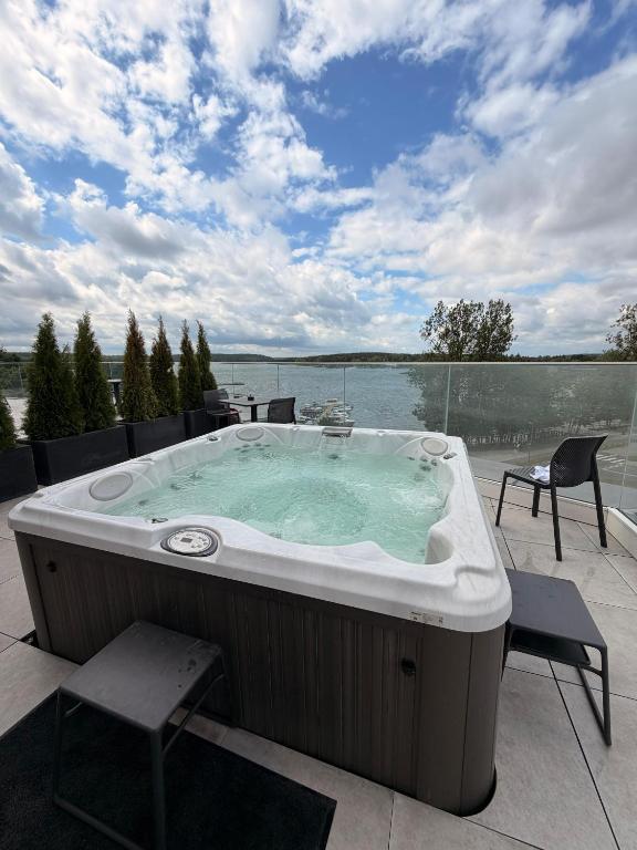a hot tub on a patio with a view of the water at Nad zatoką Ukiel apartamenty przy jeziorze in Olsztyn