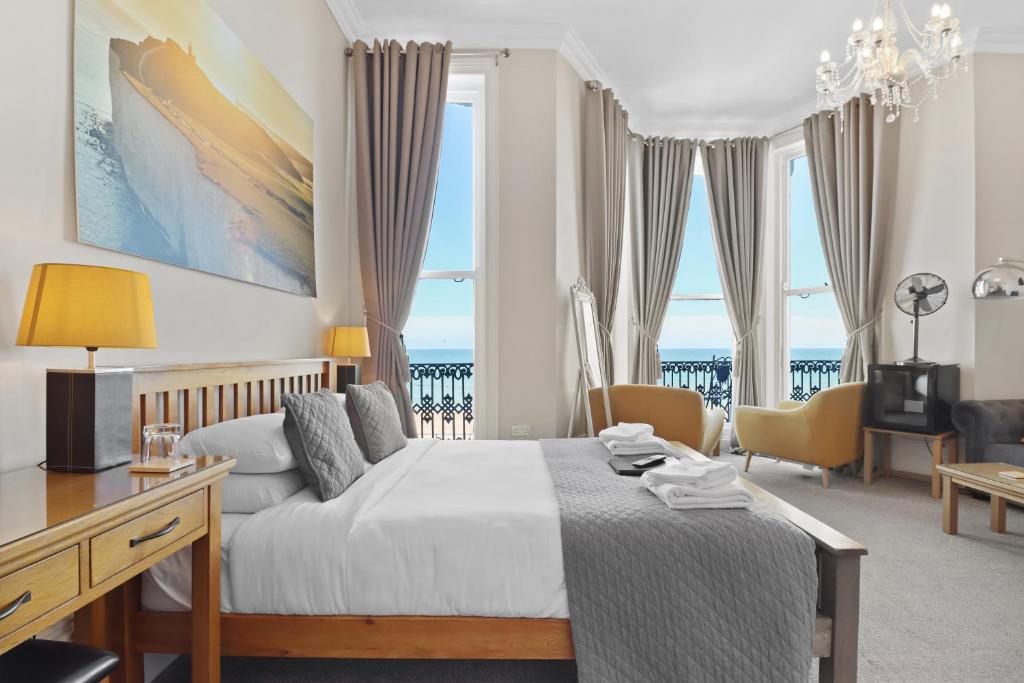 a bedroom with a bed with a desk and chairs at Beach Front Guest House in Eastbourne