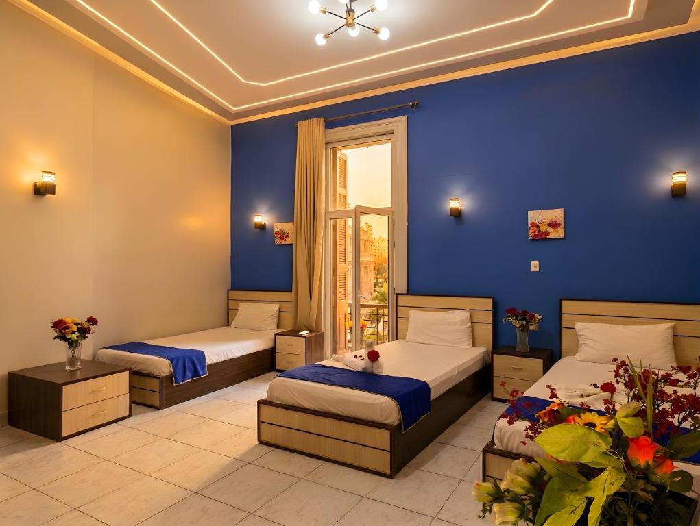a bedroom with two beds and a blue wall at Royal Hostgram and Suites in Cairo