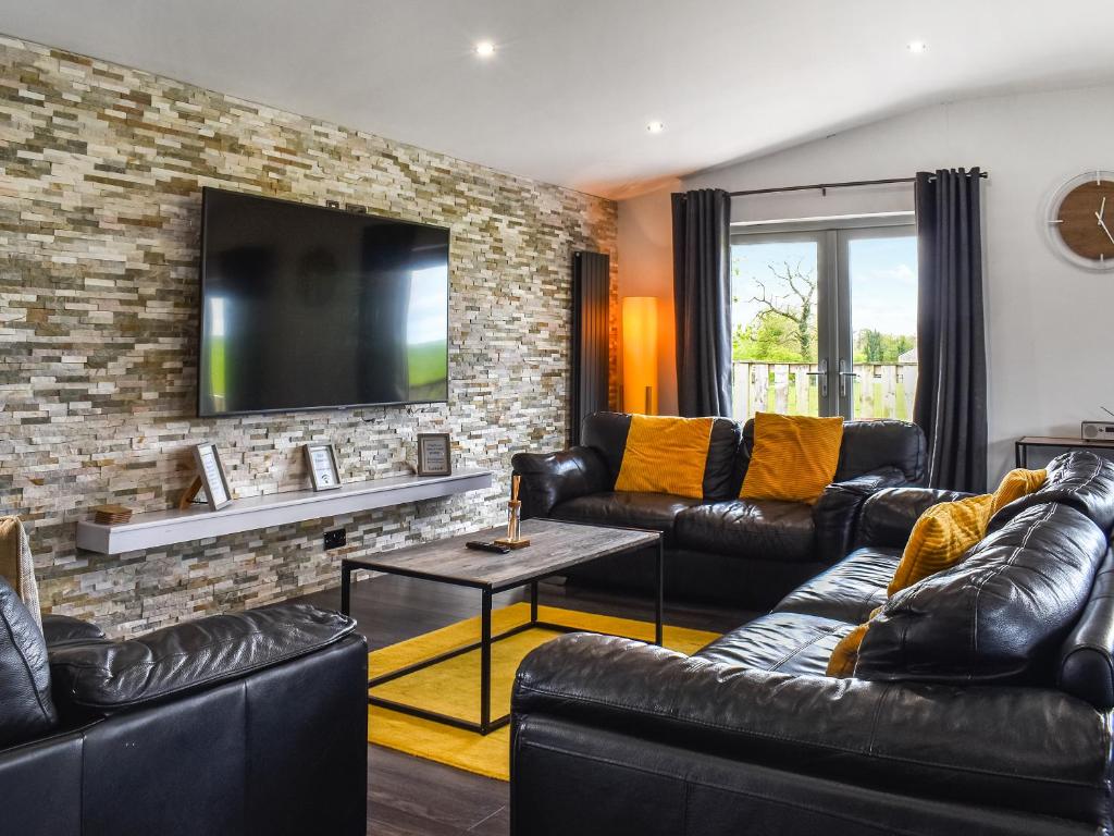 a living room with leather furniture and a brick wall at The Barbon - Uk47033 in Kirkby Lonsdale