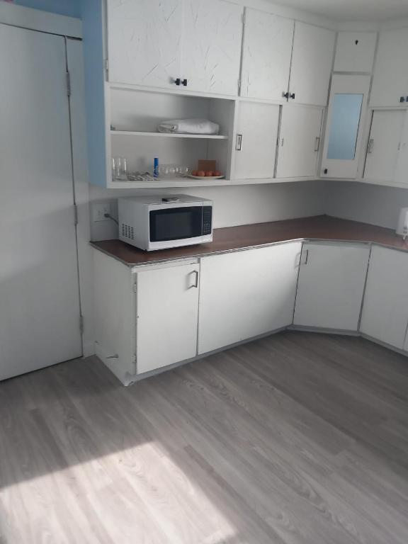 a kitchen with white cabinets and a microwave at Highway 17 Space Share accommodation in Thessalon