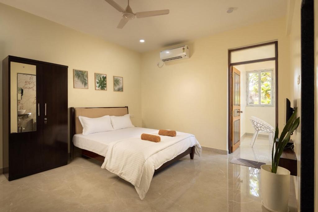 ein Schlafzimmer mit einem Bett mit weißen Laken und einem Ventilator in der Unterkunft coco haus in Canacona