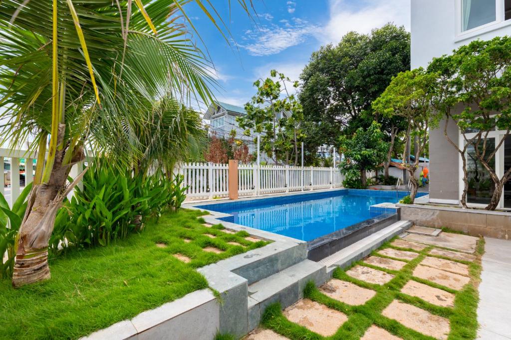 a swimming pool in a yard with a palm tree at Kegotel Luxury Villa - Bãi Tắm Long Cung in Vung Tau