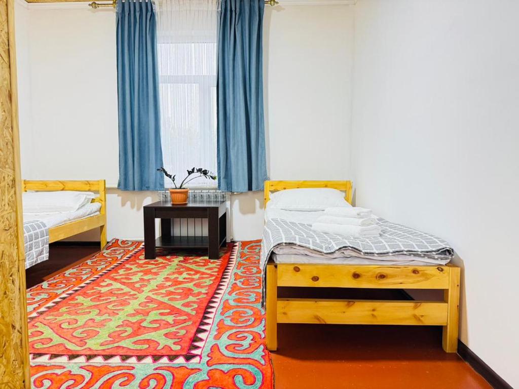 a bedroom with two beds and a rug at AI-NUR guest house in Shabdan