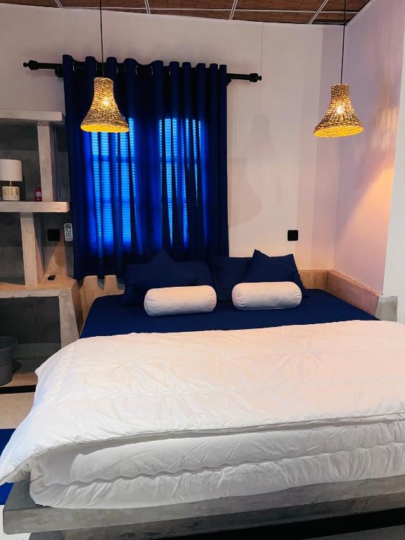a bedroom with a bed with blue curtains and two lights at Harsha Villa Dickwella in Dickwella