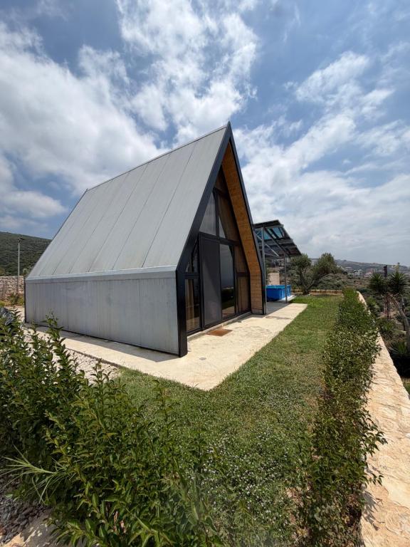 a house with a metal roof on top of a field at Moobs Sunset Cabins in Batroûn