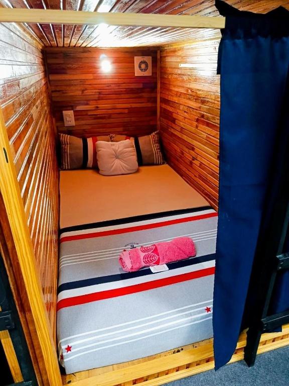 a small bed in a wooden cabin with two towels at Cuba Linda Capsule Stay in Asunción