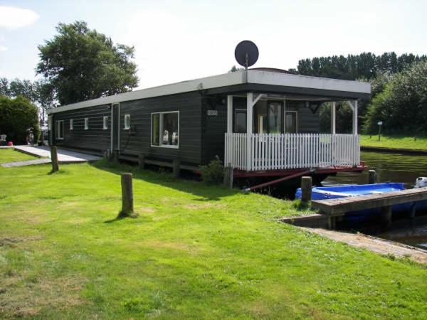 a black house sitting on the side of a river at Woonboot de Waterwoning in Irnsum
