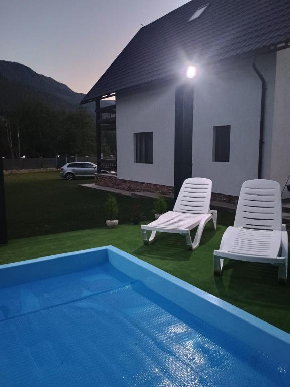 two chairs and a swimming pool next to a house at Casa Noastră in Vidra