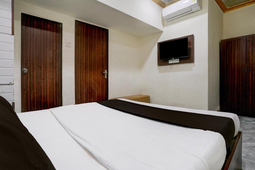 a bedroom with a white bed and a television at Hotel O Grand Villa in Mumbai