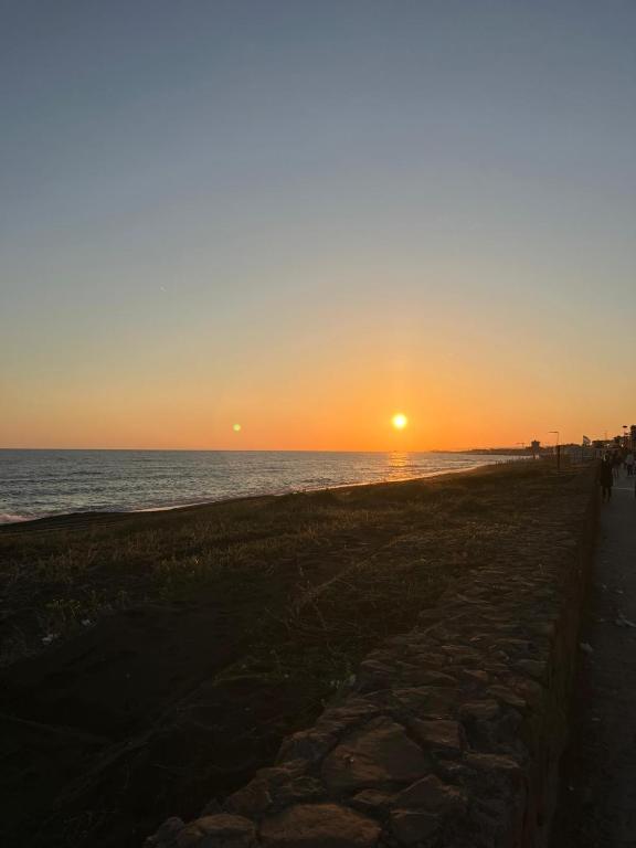 a sunset on the beach with a stone path at Casa Anna in Ladispoli
