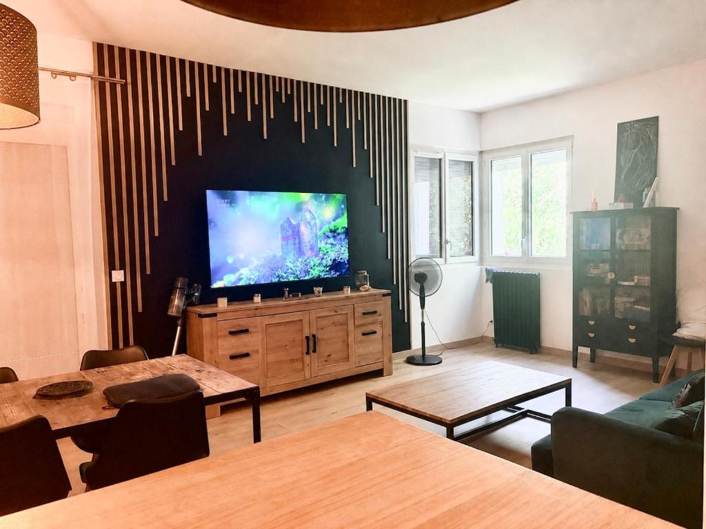 a living room with a flat screen tv on a wall at logement tranquille avec jardin in Saint-Germain-et-Mons