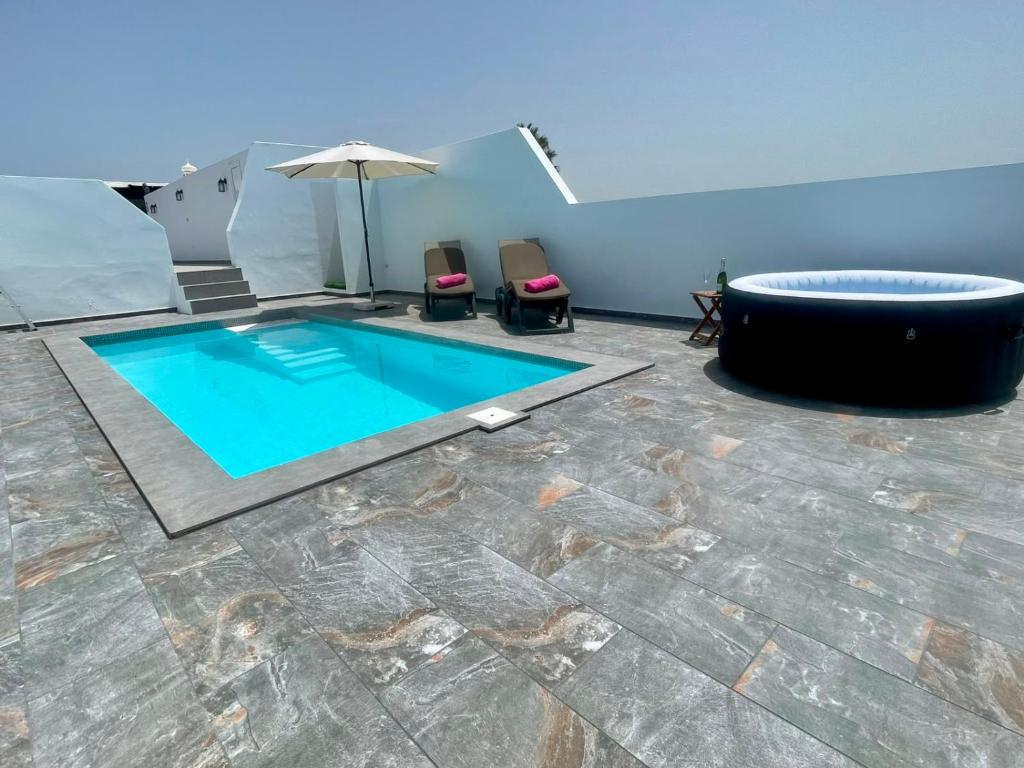 a swimming pool with two chairs and an umbrella at Apartment Orquidia - Rural Guest Apartment in Tías