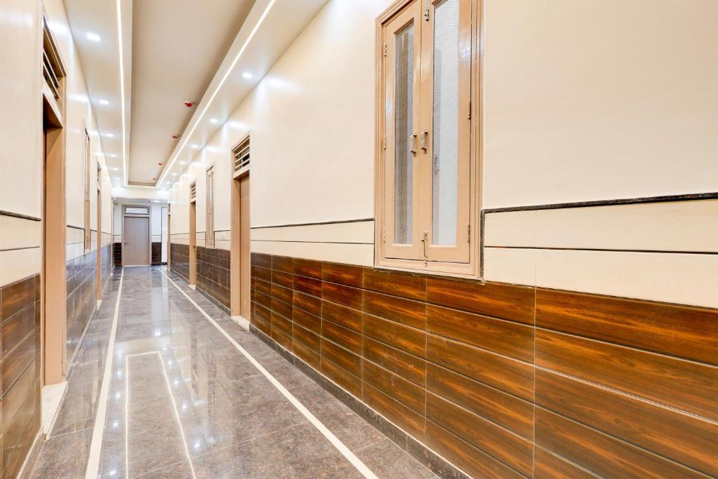 an empty corridor in a building with wooden floors and windows at Hotel O BAL GOPAL in Delhi