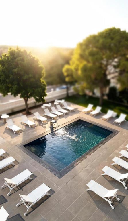 a pool with white lounge chairs and a group ofitures at Hotel Perla del Gargano in San Giovanni Rotondo