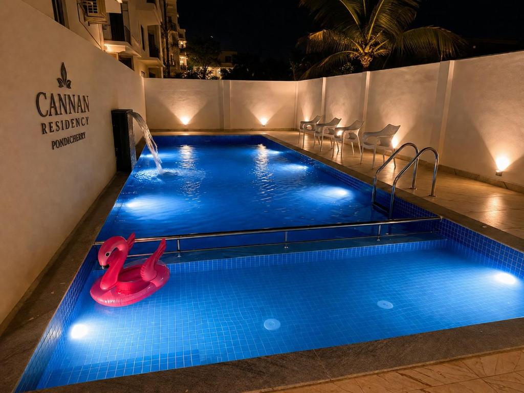 a swimming pool at night with a red slide in it at Cannan Residency Pondicherry in Pūrnānkuppam