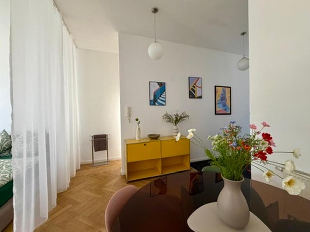 a living room with a table and a vase with flowers at Bauhaus Suite Dessau in Dessau