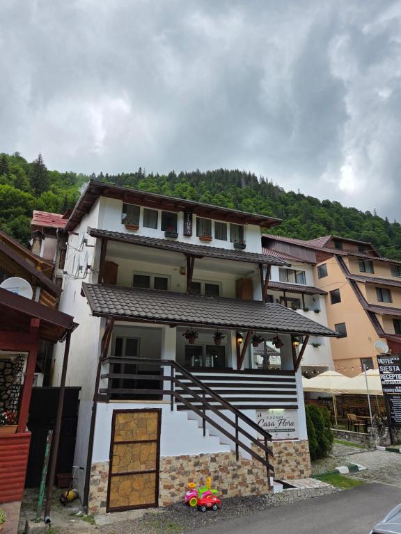 a building with a porch and stairs in front of it at Pensiunea Flora TransFăgărășan in Cumpăna